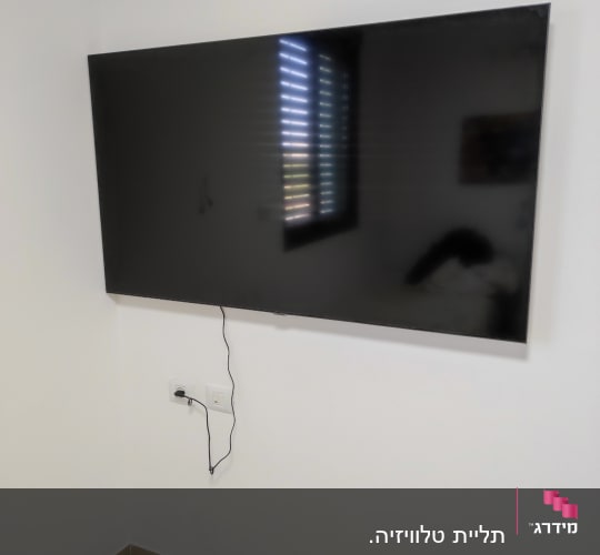טלוויזיה תלויה על הקיר עם כבל חשמל מחובר
